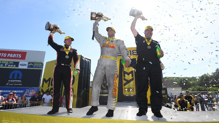 The NHRA New England Nationals winners lift their Wallys on stage.